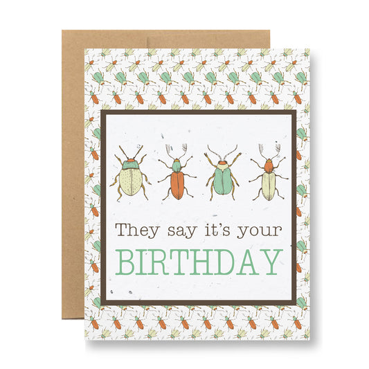 The "Plantable Greeting Card - They say it's your birthday" by My Store features a vibrant display of colorful beetles alongside the text "They say it's your BIRTHDAY," set against a backdrop of patterned insects. Made from biodegradable seed paper, this card comes with a brown envelope and can blossom into wildflowers once the celebration is over.