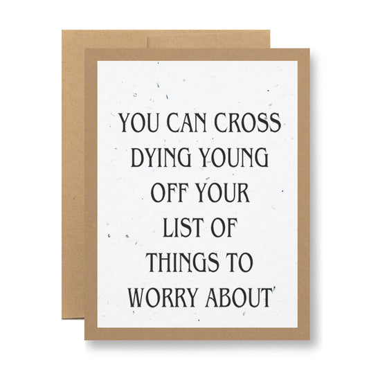 A plantable greeting card from My Store, featuring a light brown border and black text on a speckled white background, reads, "You can cross dying young off your list of things to worry about." This eco-friendly card is made from seed paper and is designed to be planted, allowing vibrant wildflower seeds to bloom along with your sentiment.