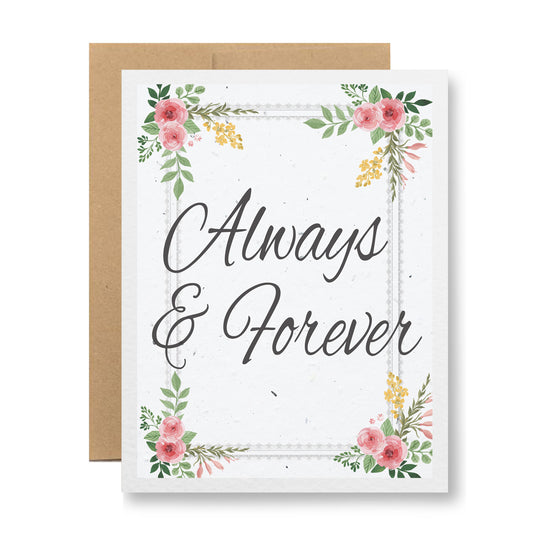 The Plantable Greeting Card - Always & Forever by My Store features an elegant script with "Always & Forever," embellished with pink and yellow flowers and green leaves in the corners. Crafted from handmade seed paper, it encourages planting wildflower seeds. Accompanying the card is a simple brown envelope.