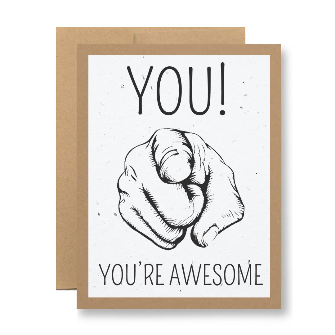 Discover the "Plantable Greeting Card - You! You're awesome" from My Store, featuring a hand-drawn illustration of a finger pointing outward. The text 'YOU!' is displayed above the image, while 'YOU'RE AWESOME' appears below. Crafted on biodegradable, handmade seed paper embedded with wildflower seeds, this card includes a brown border and comes with an envelope.