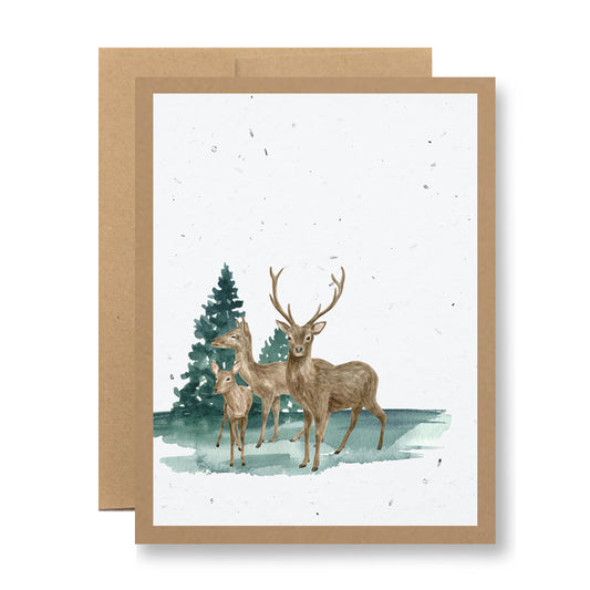 Introducing the "Plantable Greeting Card - {family of deer}" by My Store, featuring a beautiful watercolor illustration of three deer standing before snow-covered pines. Crafted on handmade seed paper, this card's natural brown background enhances its rustic, nature-inspired charm. Plant it to grow wildflower seeds and watch nature bloom.