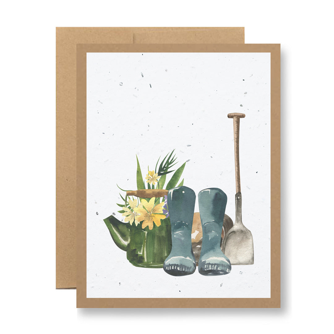 Plantable Greeting Card - {garden boots and shovel} by My Store: This illustrated card showcases a gardening scene with a watering can full of flowers, blue boots, and a shovel. Crafted from recycled cardstock, it features a neutral background framed with a brown border.