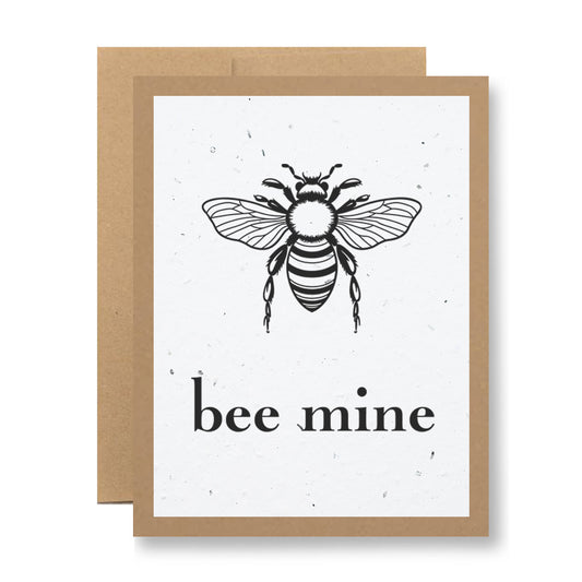 Introducing the "Plantable Greeting Card - Bee mine" by My Store, this charming card showcases a black and white bee illustration with the phrase "bee mine." Made from biodegradable card material, it features a minimalist design complemented by a brown border and background. The handmade seed paper inside contains wildflower seeds, ready to bloom when planted.