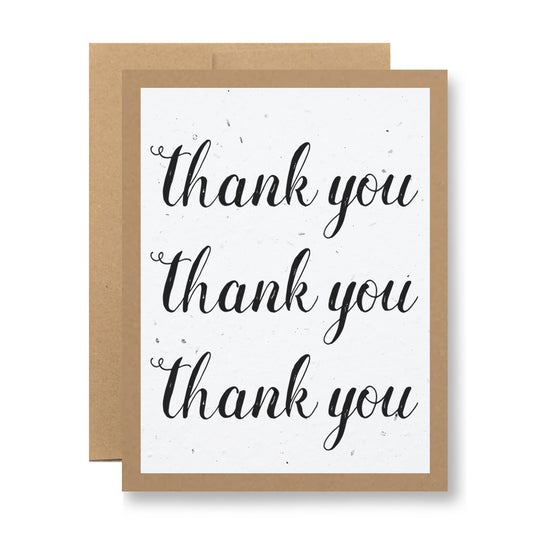 The Plantable Greeting Card - Thank you, thank you, thank you by My Store is a beautifully designed card made from handmade seed paper. It features an elegant brown border and the phrase "thank you" scripted three times in black on a white background. Behind it lies another card that pledges blooming wildflower seeds when planted.