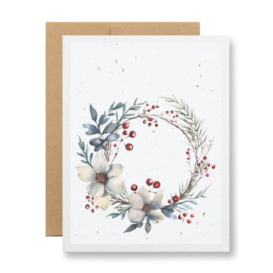 Introducing the Plantable Greeting Card - {winter wreath} by My Store. This card is beautifully crafted on handmade seed paper, showcasing a delicate floral wreath composed of white flowers, red berries, and sprigs of greenery against a plain white background. It comes with a biodegradable brown envelope.